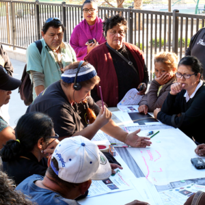 A group of community members gather around plans for urban development